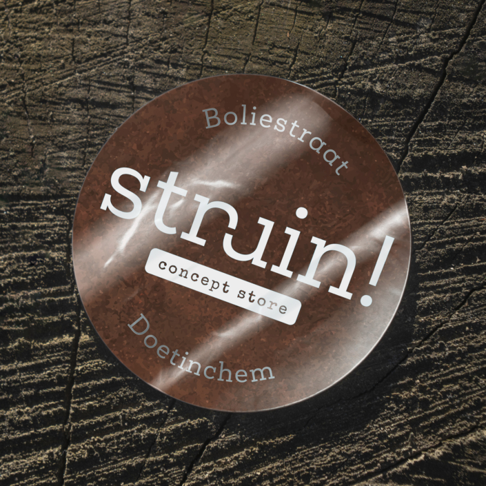 Ronde sticker op zilverpapier met cortenstaalmotief en het logo van Struin! Concept Store in dekwit