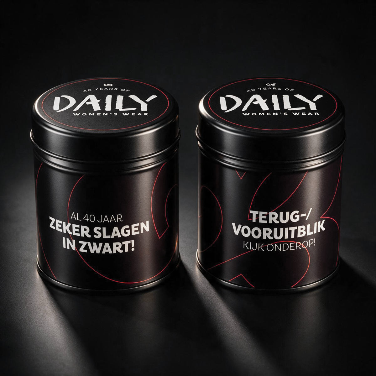Snoepblik jubileumcadeau Daily Women's Wear Twee zwarte snoepblikken met rode lijnvoering en de tekst 'Al veertig jaar zeker slagen in zwart' en 'Terug-/vooruitblik, kijk onderop' voor het 40-jarig jubileum van Daily Women's Wear