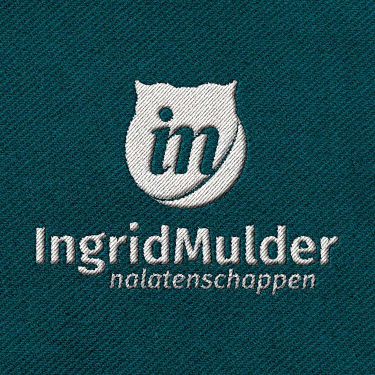 Geborduurde uitvoering van het logo van Ingrid Mulder Nalatenschappen Het logo van Ingrid Mulder Nalatenschappen geborduurd op stof
